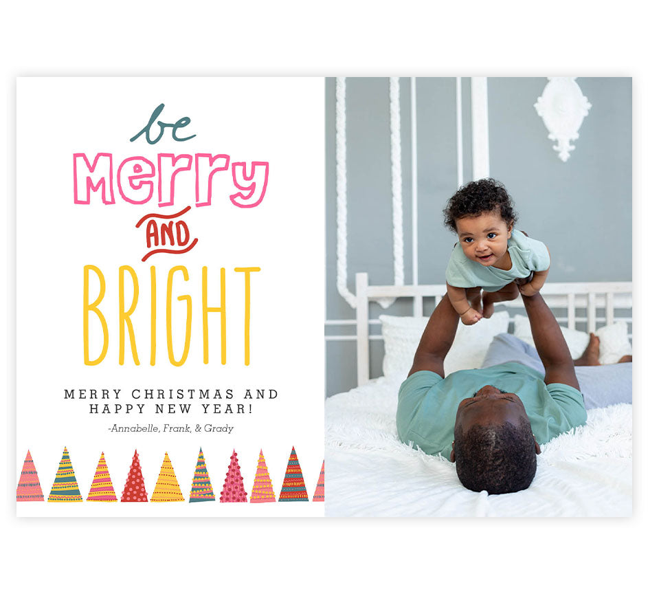 Bright Christmas Holiday Card; White background with one large image spot on the right side, colorful trees across on bottom left side with fun typography on the top left "Be Merry and Bright"