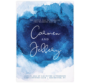 Dramatic Blue Wedding Invitation; White background with deep blue watercolor in the middle, large white text for the names and small details below in blue.